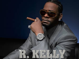 R Kelly身穿灰色西裝，手持雪茄，佩戴鑲鑽手錶和太陽眼鏡。