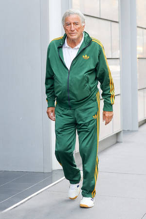 身穿綠色Adidas運動服的男性走過現代玻璃建築