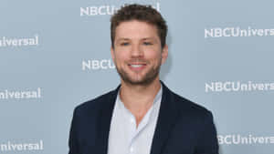 男子身穿西裝在NBCUniversal活動中對著鏡頭微笑。 — 電影 壁紙