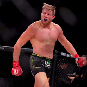 一名男性MMA戰士戴著紅色手套和藍色護齒套，在籠中慶祝勝利。 — 1:1 壁紙
