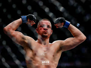 一名滿臉鮮血的勝利MMA拳手在籠內彎曲手臂。
