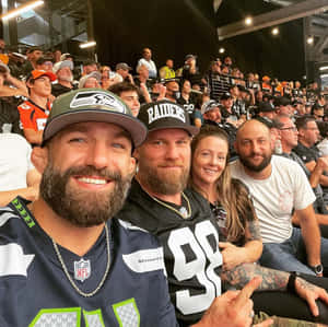 四名留鬍鬚的球迷身穿NFL球衣在體育館內微笑。