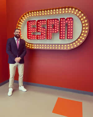男子身穿西裝在室內ESPN燈牌前擺姿勢。