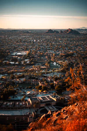 日落時分的沙漠城市全景，遠方有紅色岩層。