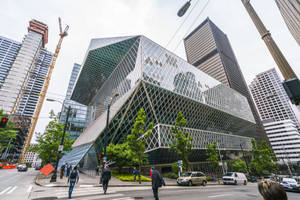 市中心現代玻璃建築，帶有鑽石圖案，有行人和汽車。