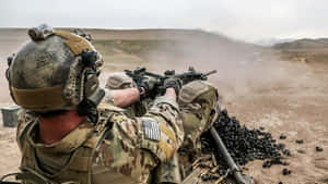 士兵在沙漠戰場上發射機槍，周圍散落著用過的彈殼。 — 槍 壁紙