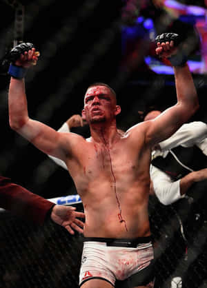 血跡斑斑的MMA拳手在雨濕的籠內高舉雙拳慶祝勝利。