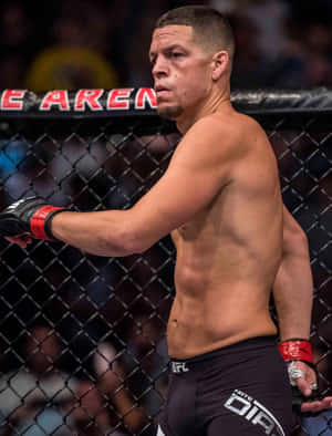 一位赤裸上身的MMA拳手穿著黑色短褲和紅色手套站在八角籠內。
