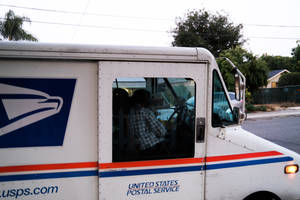 住宅區街道上，USPS送貨車司機穿著格仔恤衫。