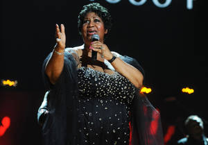 一位身穿黑色亮片裙的女性在溫暖燈光的舞台上對著麥克風唱歌。