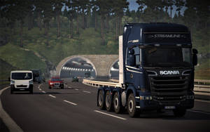 藍色 Scania 貨車在山區高速公路上駛向隧道，背景為森林。