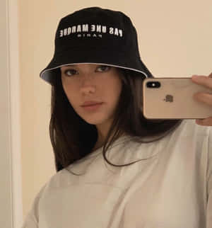 年輕女性戴著黑色漁夫帽和白色襯衫對著鏡子自拍。