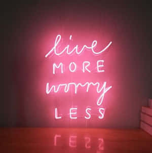 牆上寫著 live more worry less 的粉紅色霓虹燈牌，地板上有倒影。