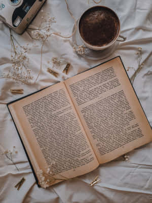 打開的書，配以咖啡和乾花，放在白色床單上供閱讀。 — 美學 壁紙