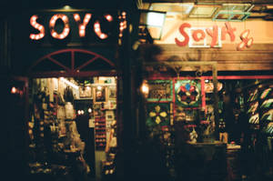 夜晚景觀，兩間溫暖照明的復古商店，帶有發光招牌和商品展示。