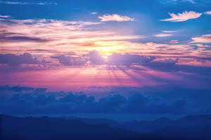 夕陽穿過多彩的雲層，照耀在山脈之上。