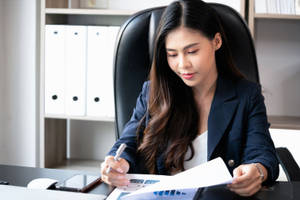 女商人在現代辦公桌上簽署文件。
