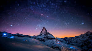 在星空暮色天空下，帶有紫色和橙色色調的白雪覆蓋的山峰。