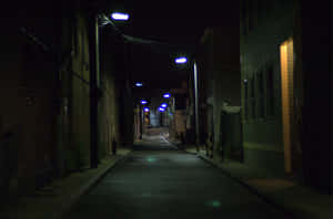 夜晚被藍色街燈照亮的黑暗城市小巷，兩旁有建築物。 — Cavetown 壁紙
