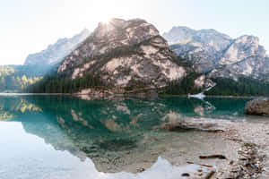 阿爾卑斯山倒映在綠松石色湖泊中，陽光穿透山峰。