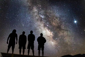 四個人剪影在星空夜空下，銀河系清晰可見。