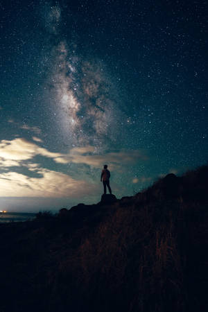 夜晚站在山上觀看星星和銀河的人