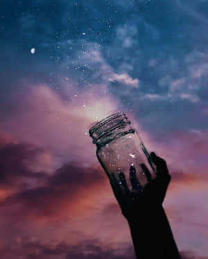 在暮色天空背景下，一隻手拿著裝滿星星的罐子的剪影。