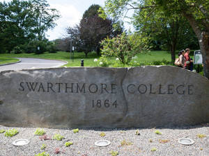 Swarthmore College 石牌，人們在校園草地上行走。