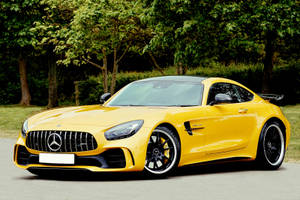 黃色 Mercedes-AMG GT R 跑車停泊在戶外，靠近綠樹。 — 汽車 壁紙