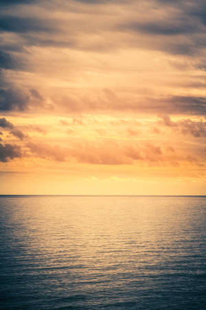 寧靜的海平線，閃耀著夕陽色彩和柔和的雲朵。