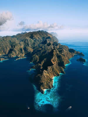 崎嶇的叢林島嶼，有碧綠色的潟湖和船隻在深藍色的海洋中。