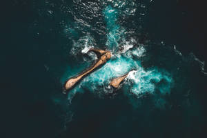 洶湧海洋中鋸齒狀岩石的航拍，帶有泡沫波浪。 — 海洋 壁紙