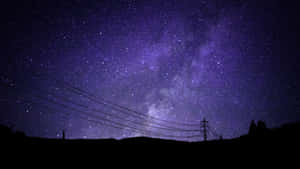 紫色星空夜空，銀河在黑暗山丘和電線上。