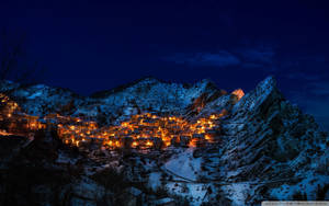 在繁星點點的夜空下，被溫暖燈光照亮的雪山村。
