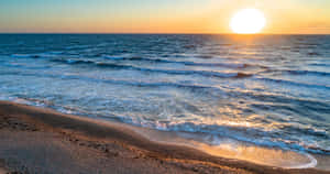 夕陽下的海洋，海浪沖刷著沙灘。