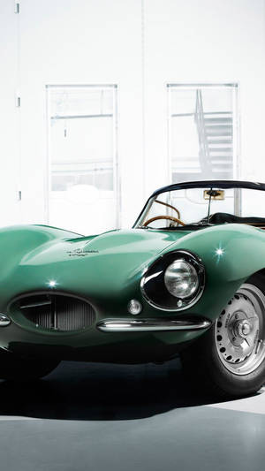 明亮的白色攝影棚中的復古綠色Jaguar E-Type跑車。