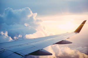 飛機機翼在金色夕陽中翱翔於雲層之上