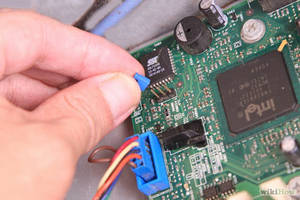 手將藍色電纜連接到帶有Intel晶片的綠色電路板。