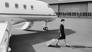 空姐在停機坪上拖著行李箱在私人飛機旁