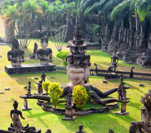 神聖的花園，有石雕佛像和頭骨，周圍環繞著棕櫚樹。 — 綠色動態圖 壁紙