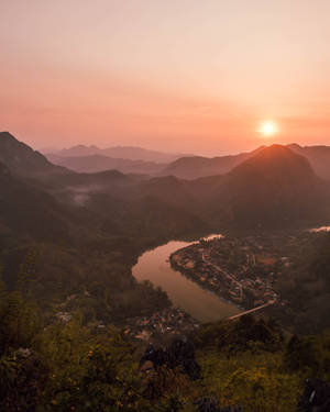 夕陽照耀著山谷，蜿蜒的河流和下方的小村莊 — 4:5 壁紙