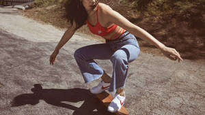 女子在明亮的陽光下在裂開的路面上玩滑板。 — 型格 Nike 壁紙