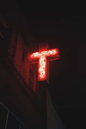 夜間安裝在磚砌建築物上，一個紅色霓虹十字標誌，上面寫著「JESUS SAVES」。 — 耶穌基督 壁紙
