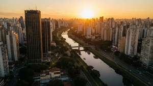 夕陽籠罩著高樓林立的密集城市，河流蜿蜒穿過城市景觀。