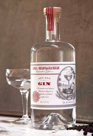 一瓶 St George Dry Rye Gin 旁邊放著一個 coupe 杯，放在木質表面上。