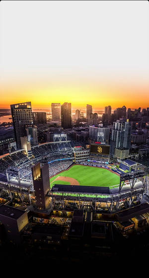 夕陽西下，棒球場內坐滿球迷，背景是城市天際線。