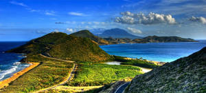 海岸山丘，有蜿蜒的道路和碧綠的海水，在明亮的藍天下。 — 島嶼 壁紙