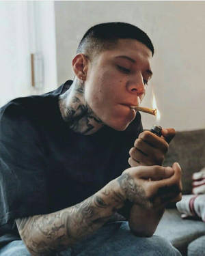 有紋身的男士在室內梳化上點燃大麻煙。
