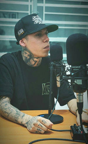 有紋身男人戴帽喺錄音室用咪高峰錄音