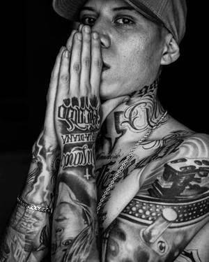一個有紋身嘅男人戴住帽，喺黑白相入面將手放喺面附近。